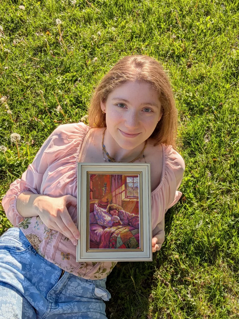 Morgane Cachia, illustratrice et artiste peintre à Montréal, assise dans l’herbe avec une de ses peintures